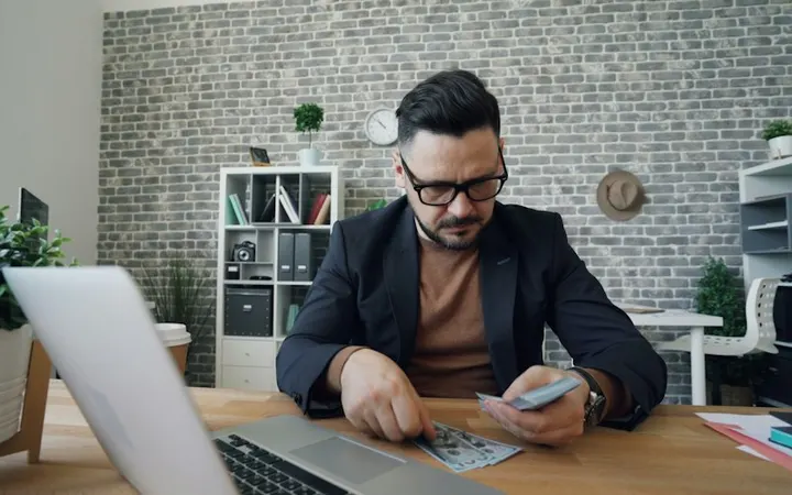 Professional reviewing figures at a desk with a laptop