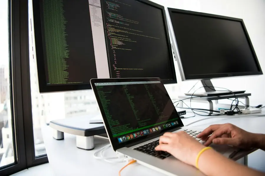 IT engineer configuring a new laptop at a desk with monitors
